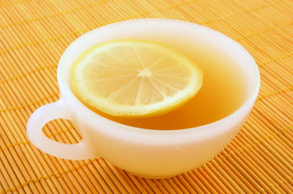 Cup of tea with lemon on a rattan mat in warm golden light.